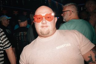 A man in a club wearing heart-shaped sunglasses