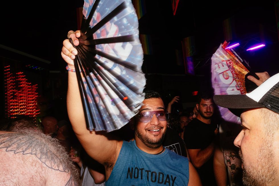 A man in sunglasses excitedly waving a fan on the dance floor