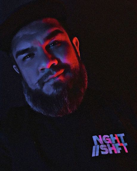 A bearded man wearing a shirt with the Night Shift logo