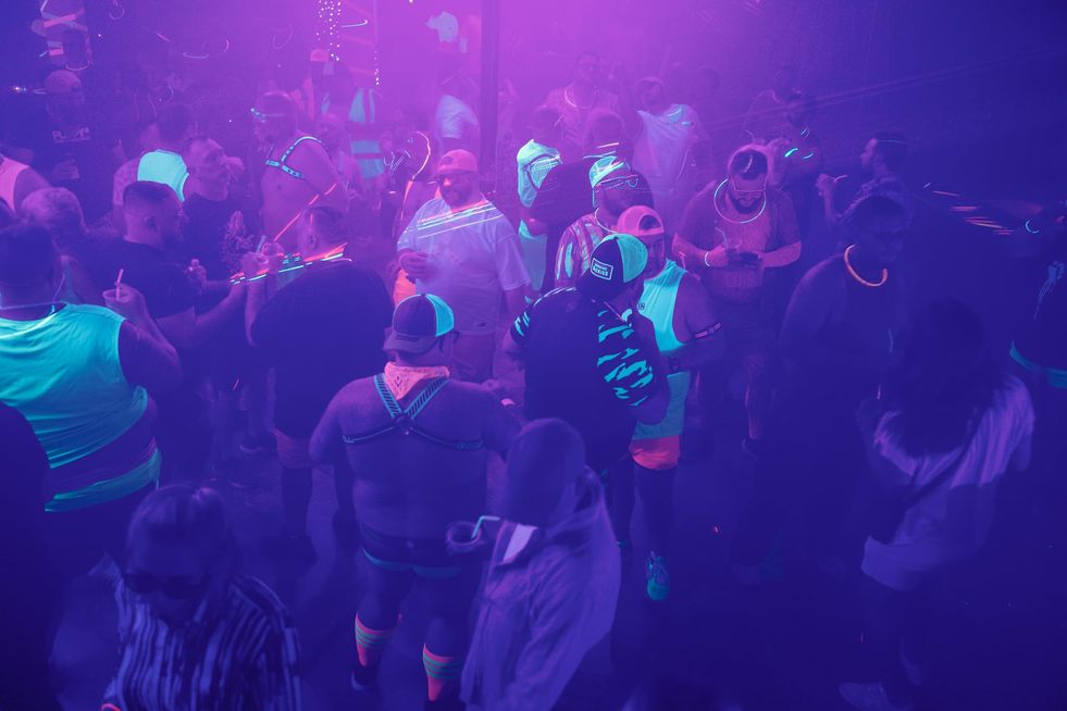 A large group of people wearing glowing clothing and accessories dancing in a club