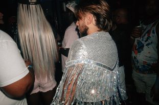 A man in a club wearing a sequinned shawl