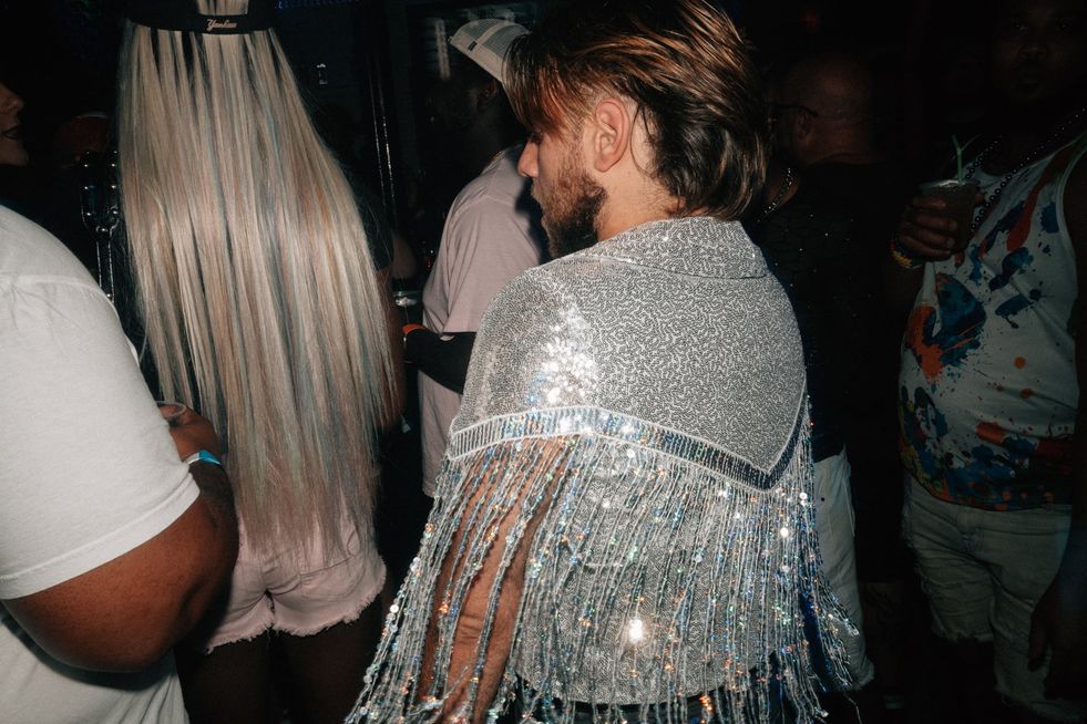 A man in a club wearing a sequinned shawl