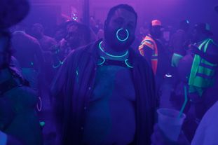 A man in a club with a large, glowing nose ring
