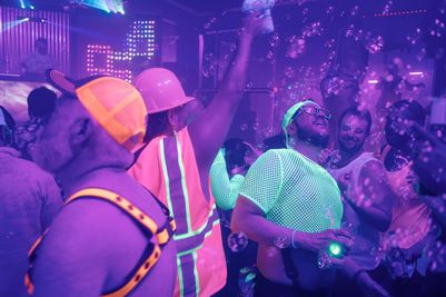 A large group of people wearing glowing clothing and accessories dancing in a club
