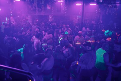 A large group of people wearing glowing clothing and accessories dancing in a club