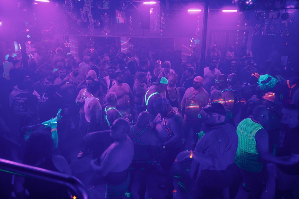 A large group of people wearing glowing clothing and accessories dancing in a club
