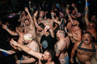 A group of mostly shirtless men dancing in a club