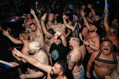 A group of mostly shirtless men dancing in a club