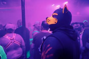 A group of men wearing glowing clothing and accessories dancing in a club