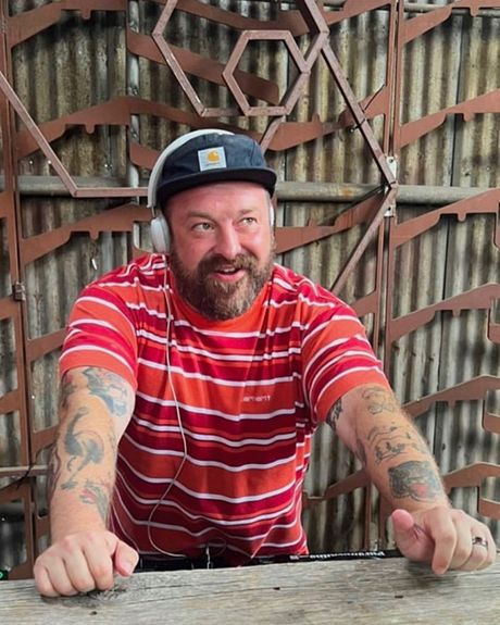 A DJ wearing headphones and a striped shirt