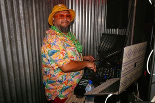 A DJ in beach apparel in the DJ booth