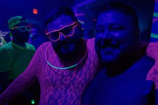 Two men smiling for the camera wearing glowing clothing and accessories