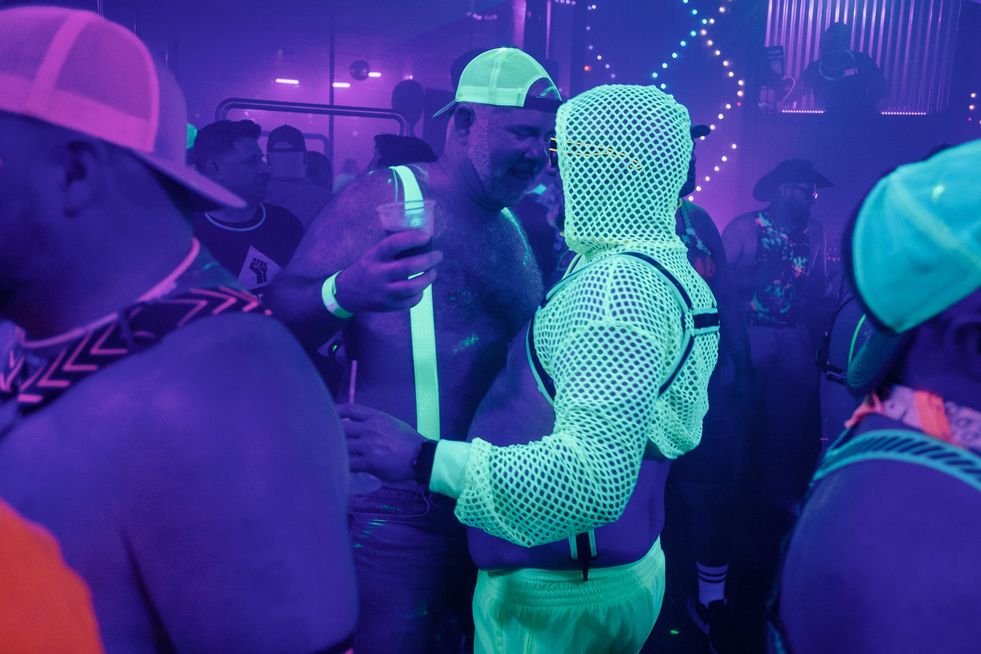 A group of men wearing glowing clothing and accessories dancing in a club