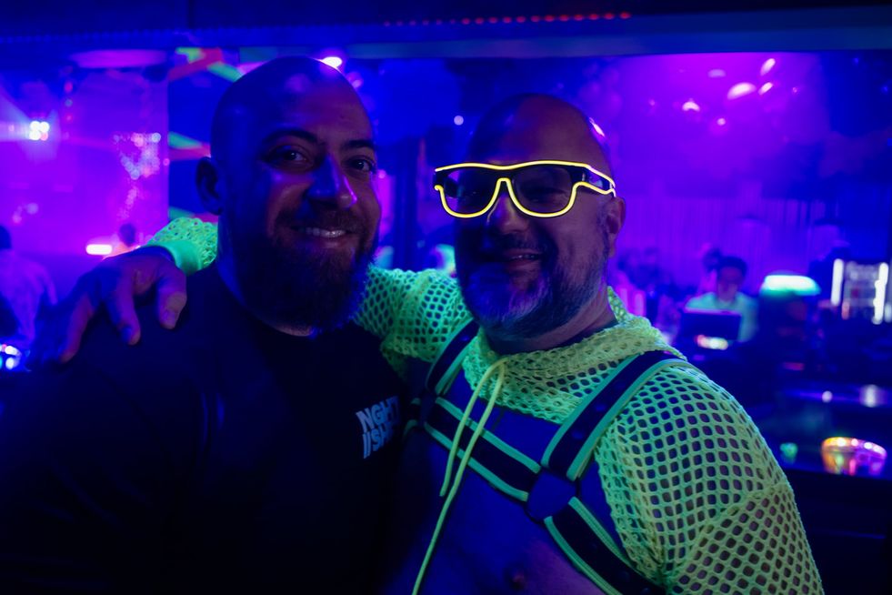 Two men smiling for the camera wearing glowing clothing and accessories