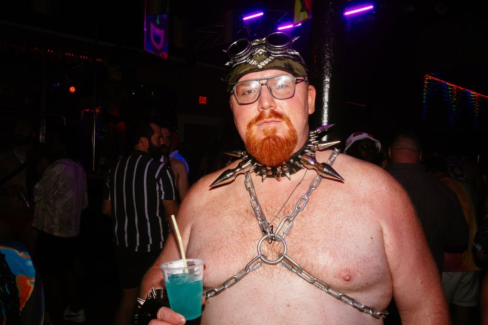 A ginger bear of a man in a chain harness, heavily spiked collar wearing a bandana and goggles on his head