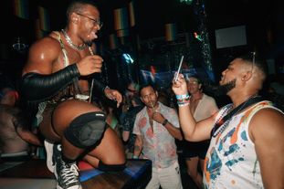 A man in a club taking a photo of a go-go dancer posing for him
