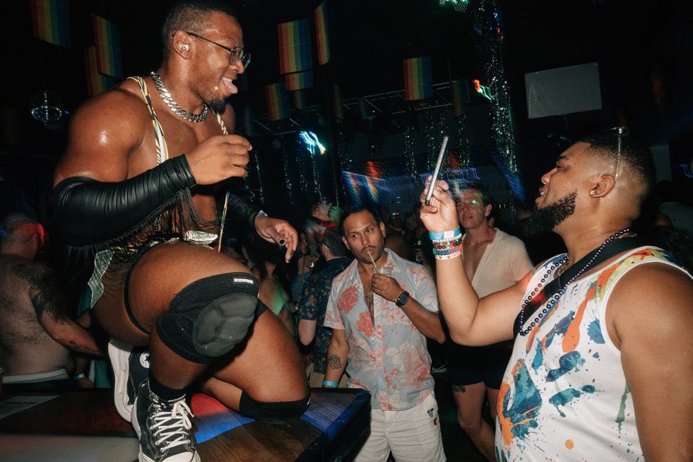 A man in a club taking a photo of a go-go dancer posing for him